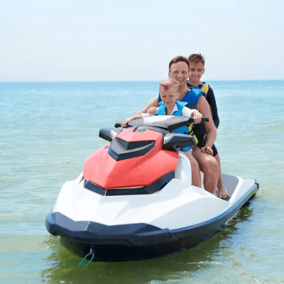 Three people riding a jet ski on calm ocean waters.