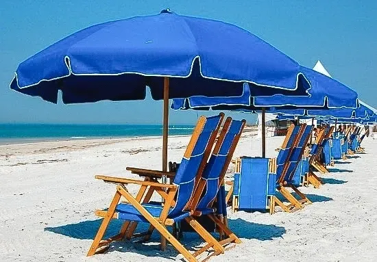 Row of blue beach umbrellas and chairs on a sandy beach.
